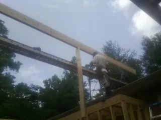 Carpenter setting a ridge beam over a new addition frame — Ice Dam Removal by Roofing Brothers in Buford