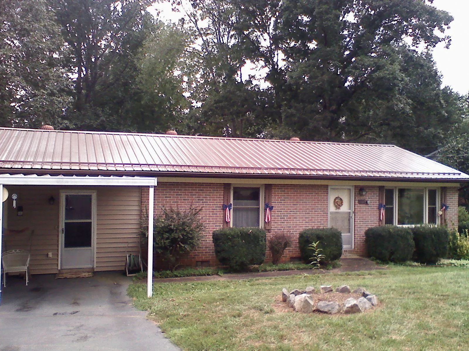 Bronze metal roof and carport on a brick ranch home — Roof Repair work by our crew in Buford