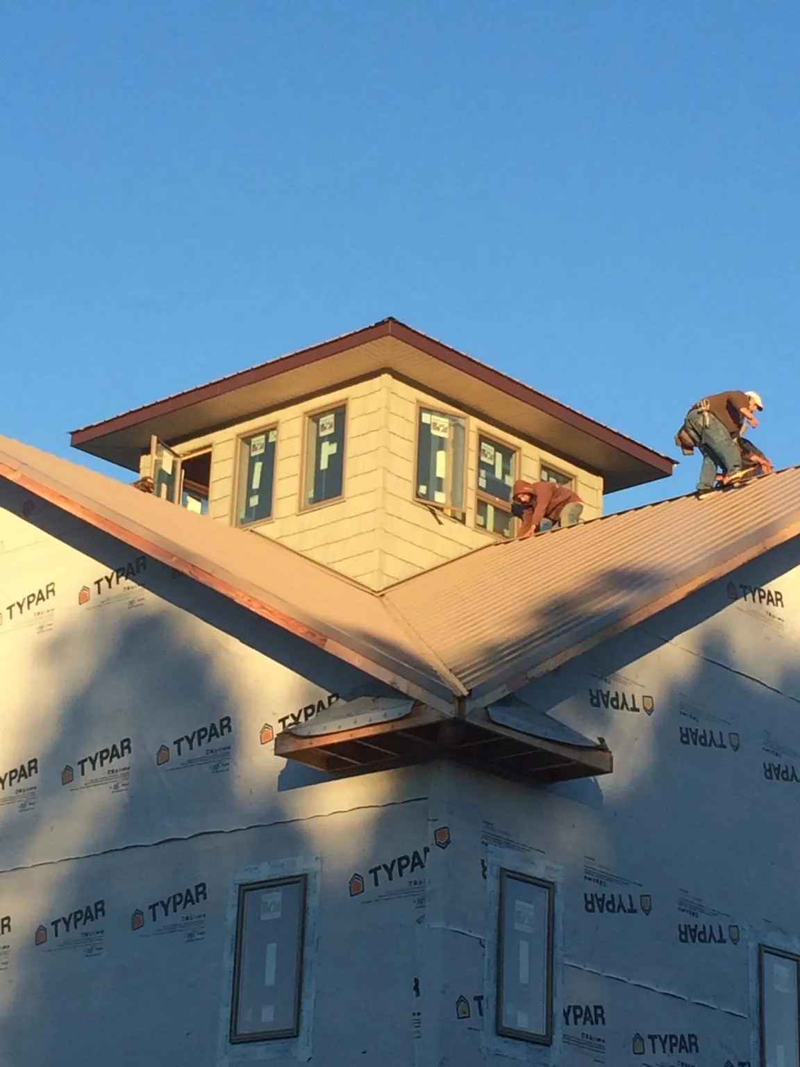 Roofers working around a rooftop cupola on a new metal roof at sunset — Roof Waterproofing in Buford by Roofing Brothers
